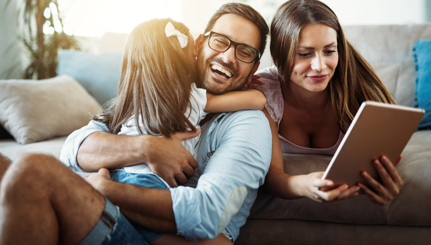 Man hugging child with woman looking at laptop